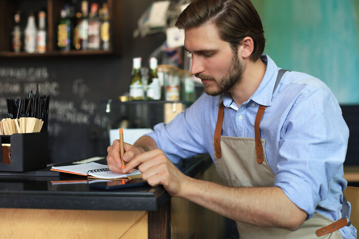 Restaurant staff writing notes at counter, sharing tales about what happens when the bill comes and the money doesn’t.