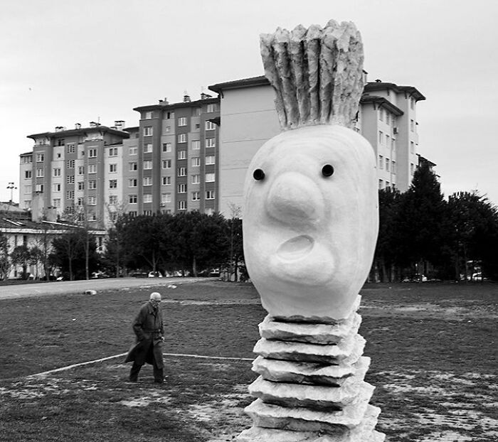 Large abstract stone sculpture on a street in Istanbul with a person walking nearby in an urban setting.