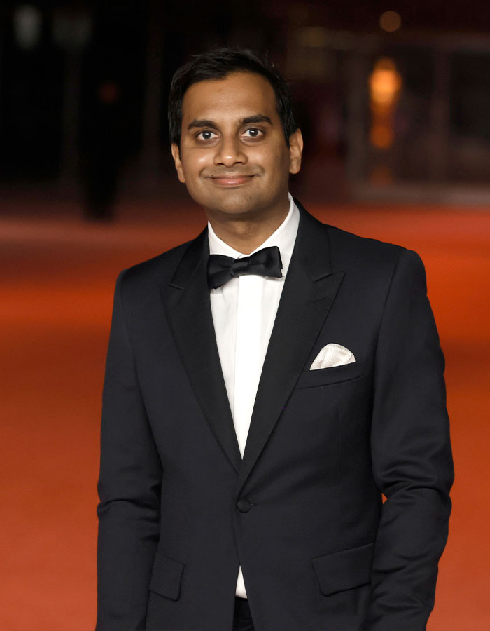 Man in a black tuxedo and bow tie smiling at an event, representing famous men who are shorter than fans imagined.