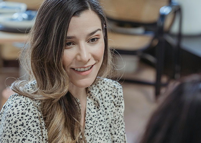 Woman smiling subtly in a casual setting, illustrating creepy things women said or did to men that left them horrified.