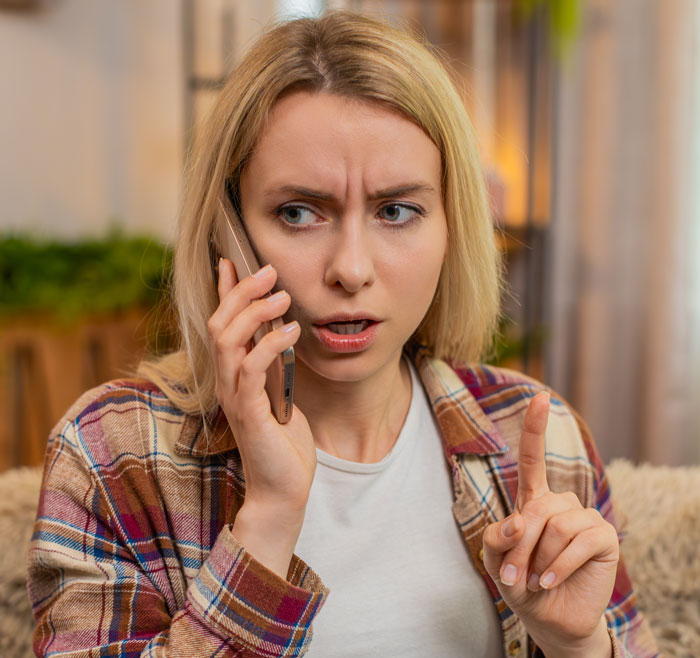 New mom on phone looking concerned and frustrated while confronting MIL over unhinged behavior at home.