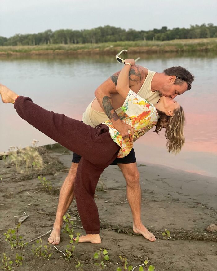 Couple sharing a romantic kiss outdoors by the water, capturing a moment linked to Kristen Bell snubs fans anniversary post backlash.