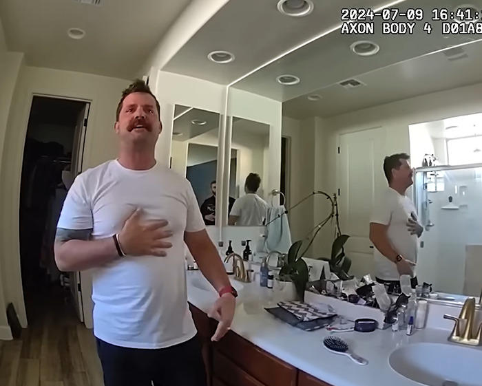 Man in a white shirt standing in a bathroom with mirrors, related to dad watched adult videos and 2YO daughter in hot car case.