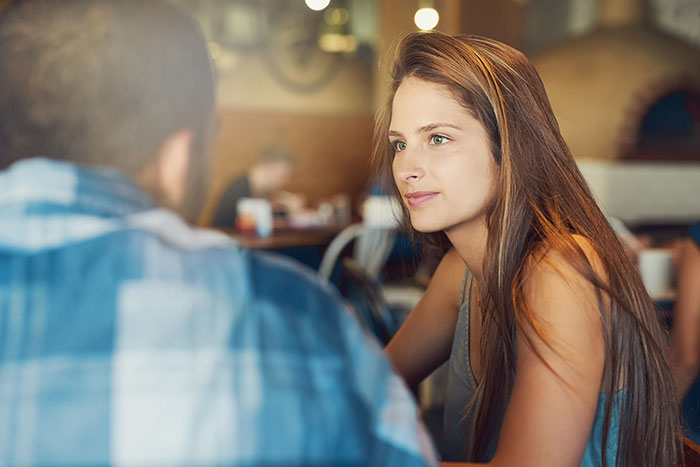 Young woman having a meaningful conversation with her boyfriend&rsquo;s grown son in a cozy caf&eacute; setting.