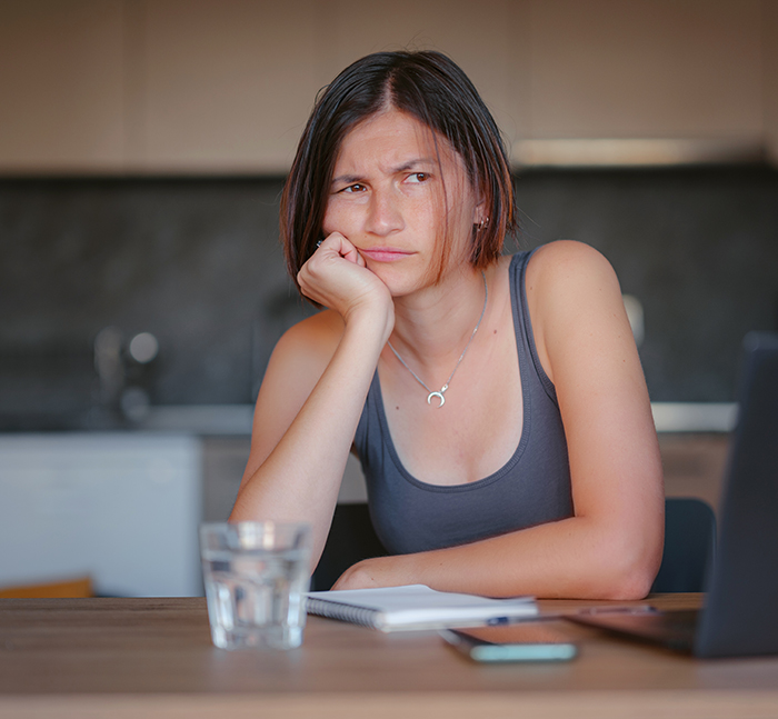 Young woman looking confused while sitting at a table, reflecting on guys deciding to buy shawls and reactions.