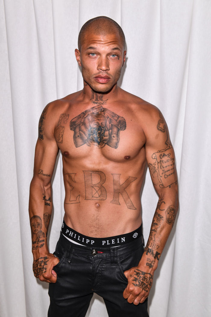 Shirtless man with tattoos including EBK on chest, posing confidently, representing world's hottest felon at 41.