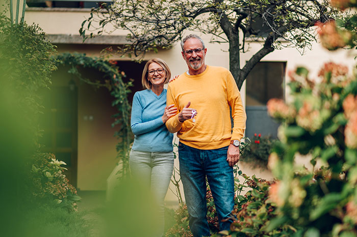 Middle-aged man and woman standing in garden, with man ready to turn on Karen mode against neighbors in block disputes.