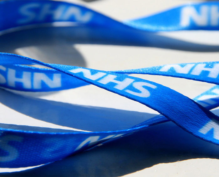 Blue NHS lanyard with white text, symbolizing UK health guidance amidst controversy over marrying your cousin benefits.