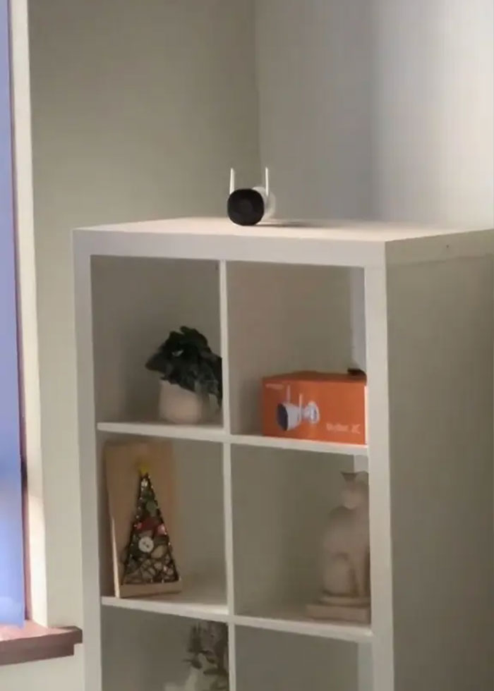 Smart home security camera on shelf inside rental house, hinting at family rush after disturbing discovery indoors.