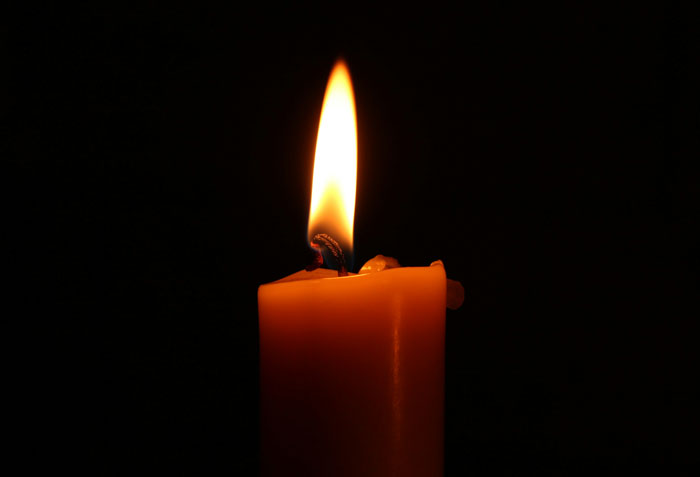 A single orange candle burning brightly in the dark, symbolizing urgency in wild we need to leave right now stories.
