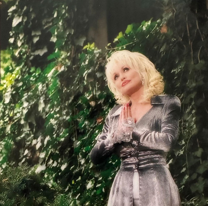 Dolly Parton's sister raising alarm and asking for prayers for the singer amid health struggles outdoors by greenery.