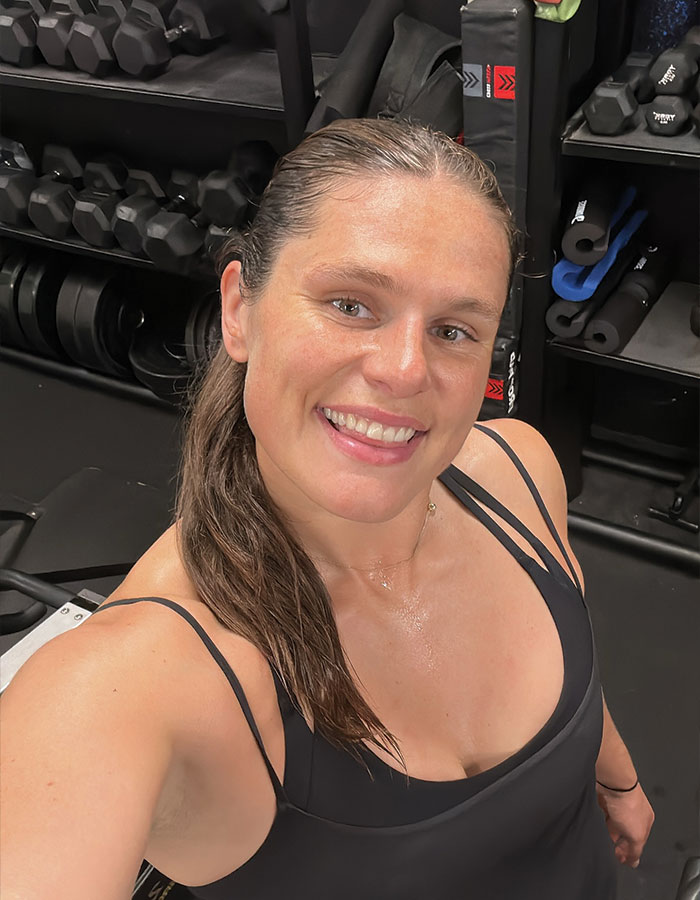 Olympic athlete Ilona Maher smiling in gym setting, challenging ideas about being considered overweight in sports.