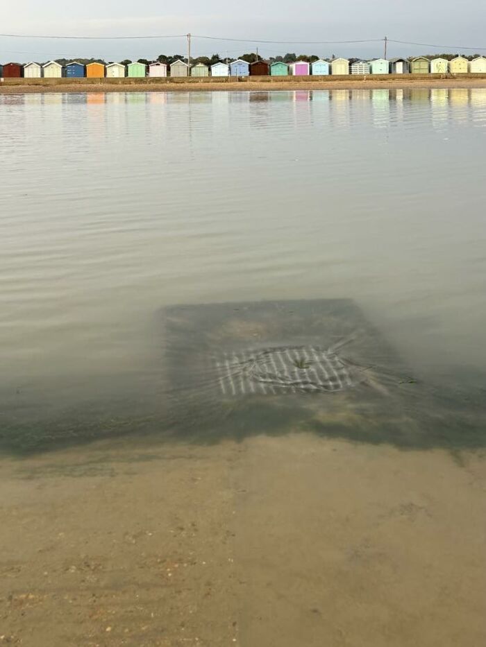 Colorful row of small houses along calm water creating a beautiful yet unnerving liminal space reflection.