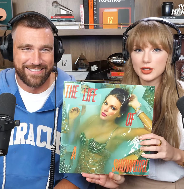 Travis Kelce and Taylor Swift fans react as he autographs her albums amid tradwife controversy in a podcast setting.