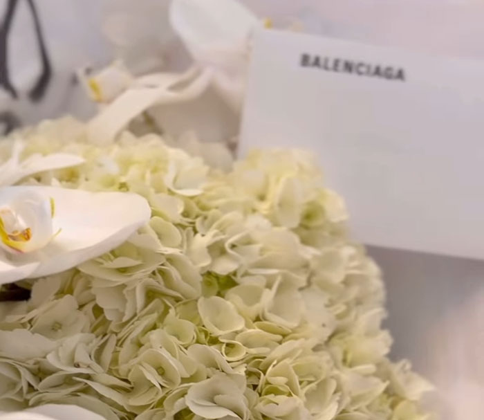 Close-up of white hydrangea flowers and an orchid with a Balenciaga card, related to Meghan Markle Paris Fashion Week event.