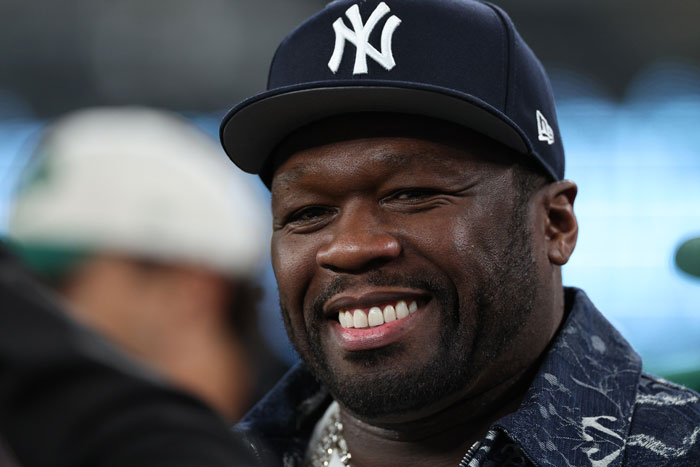 Man wearing New York Yankees cap smiling, related to hard rock cover of 50 Cent's Many Men going viral amid AI music boom