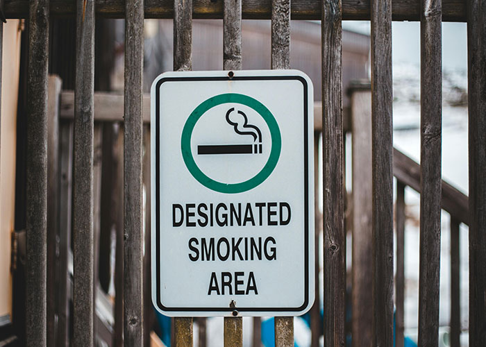 Smoking sign in a designated area, illustrating creative loopholes used against horrible bosses at the workplace.