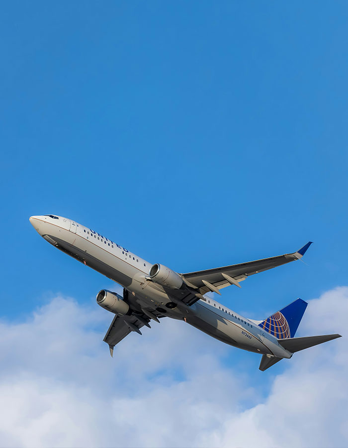 Commercial airplane flying in a clear blue sky, representing mid-flight confrontation during infidelity incident.