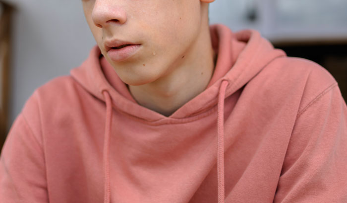 Young person in a pink hoodie with a tear on their cheek, reflecting on the worst crimes that happened in their hometown.
