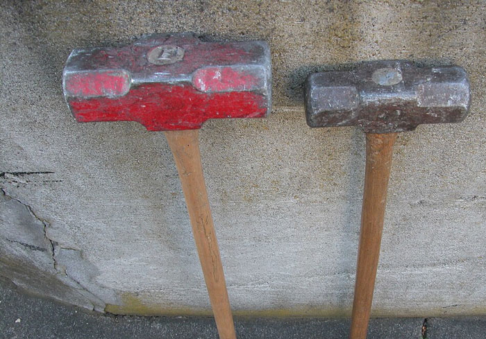 Two worn sledgehammers leaning against a concrete wall symbolizing the worst employees bosses have dealt with.