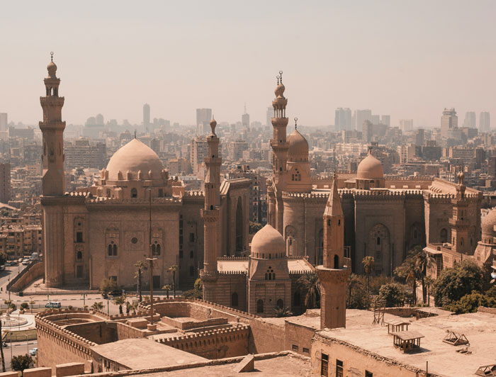 A cityscape showing old mosques and buildings in a dusty urban area, one of the places people wouldn’t revisit.