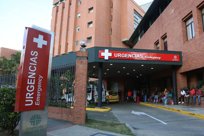 Hospital emergency entrance with people gathered outside, related to NYPD detective and cosmetic surgery case.