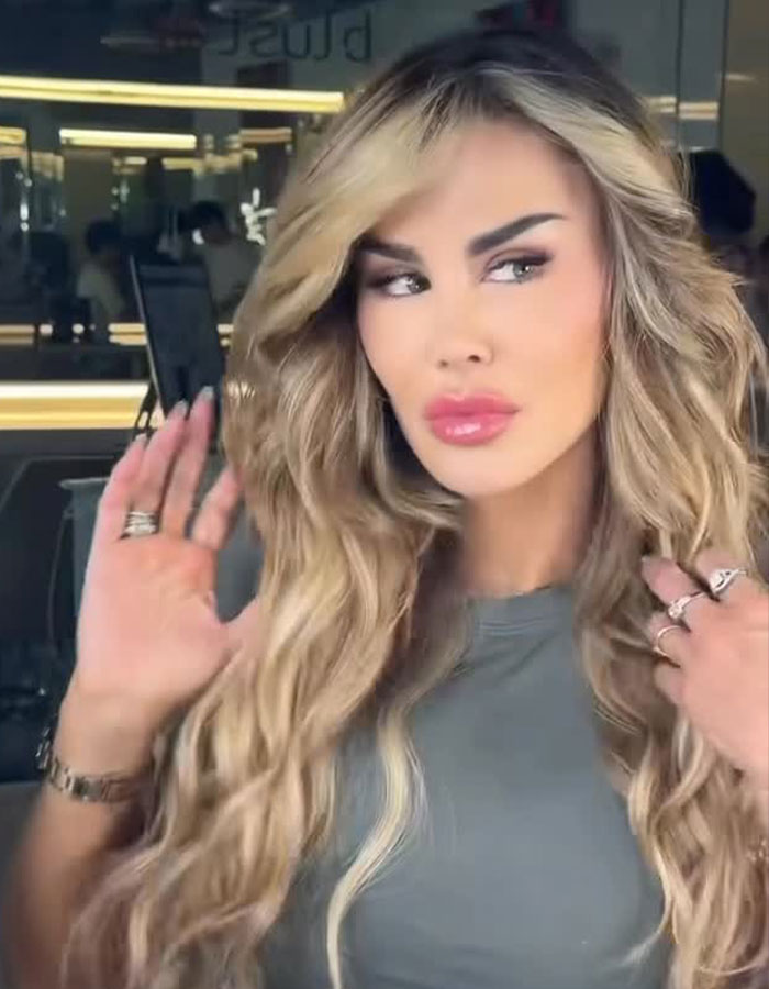 Actress with long blonde hair showcasing her eye color after controversial surgery risking blindness in a salon setting.