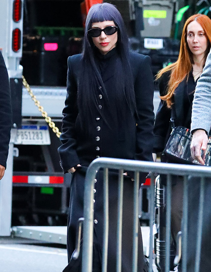 Celeb in black outfit and sunglasses walking outside amid people, highlighting tone-deaf celeb mocking lower earners.