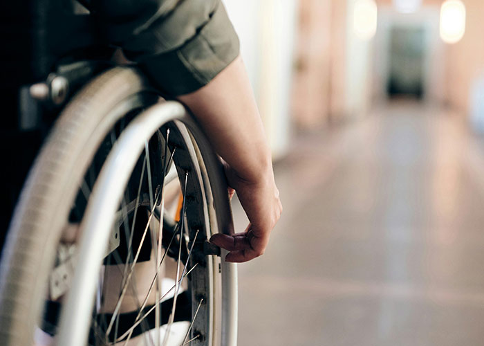 Close-up of a person’s hand on a wheelchair wheel, illustrating moments moms felt embarrassed by their kids.