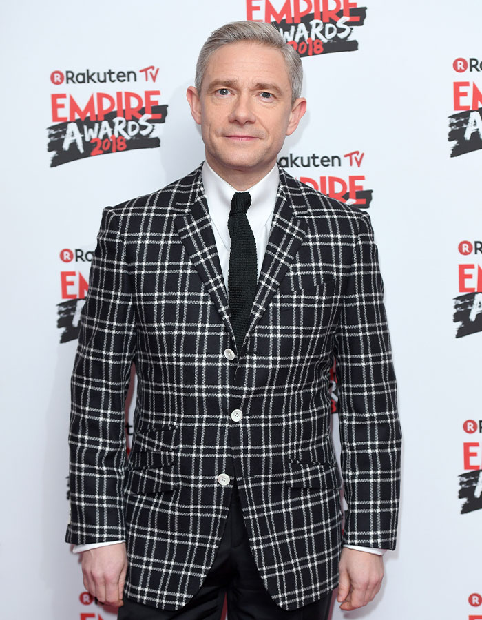 Man in a black and white checkered blazer at an event, representing famous men who are much shorter than fans imagined