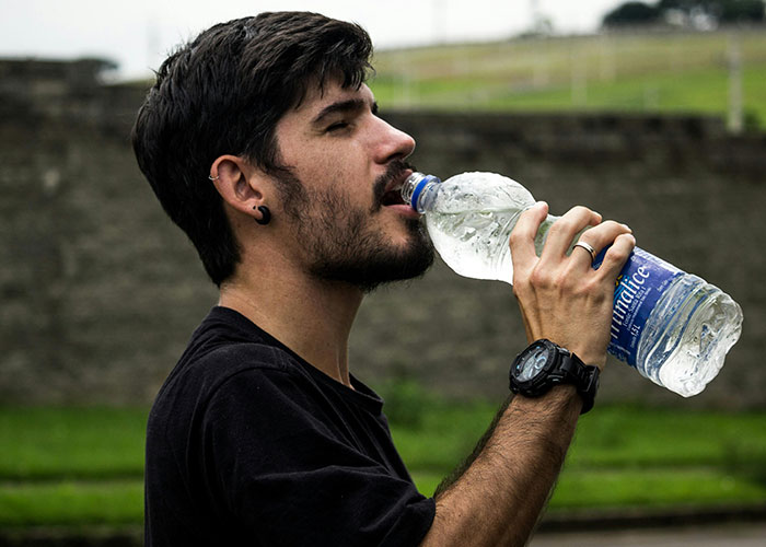 A man outdoors drinking water from a plastic bottle demonstrating simple life hacks discovered accidentally.