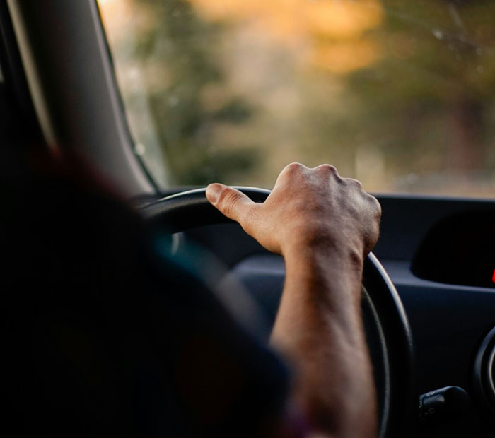 Driver's hand on steering wheel at dusk, road ahead blurred, concept for worst places travel experiences