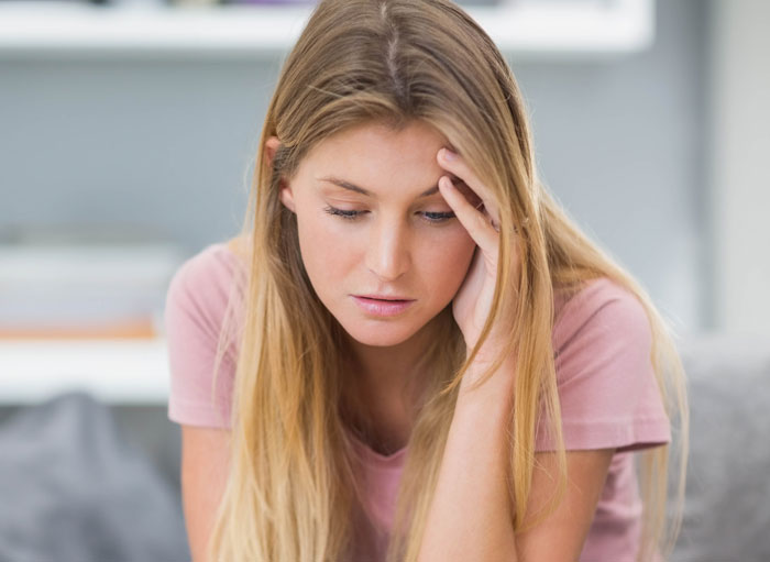 New mom sitting stressed and upset, dealing with difficult MIL behavior and family confrontation at home.