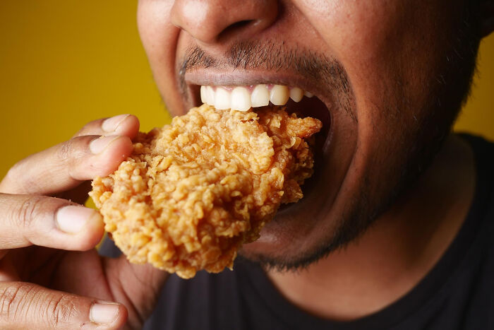 Man eating crispy fried chicken close-up showing clueless dads doing lovable things while their wives were pregnant