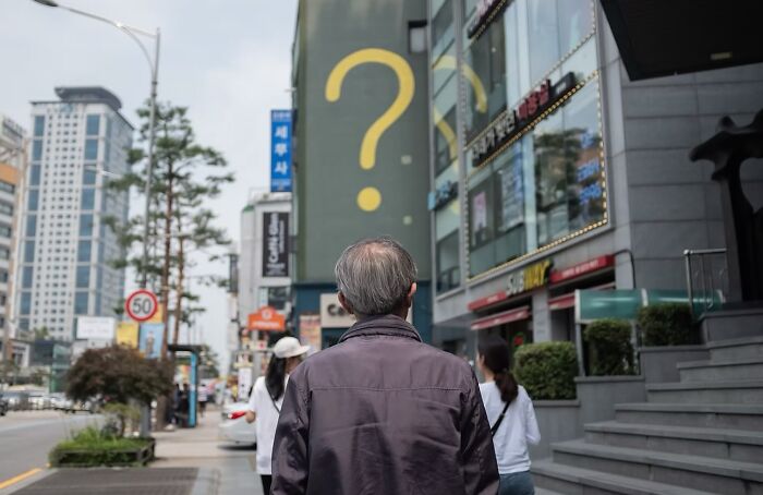 Elderly man walking on a busy street, surrounded by urban buildings, capturing beauty and wisdom of old age.