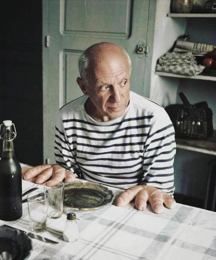 Elderly man with bread rolls on his hands sitting at a table, a street photo capturing the beauty of old age.