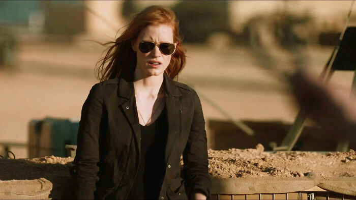 Woman with red hair and sunglasses in a black jacket outdoors, scene from movies based on true stories that feel impossible to believe