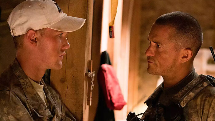 Two soldiers in a tense conversation inside a wooden building, depicting scenes from movies based on true stories.