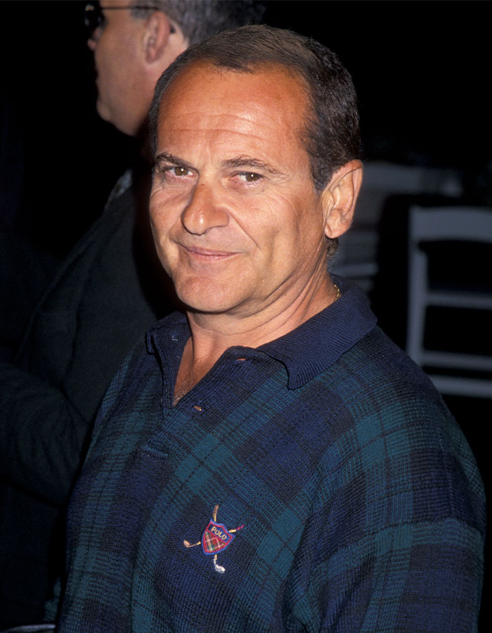 Middle-aged man in a blue plaid polo shirt smiling, an example of famous men much shorter than fans imagined.