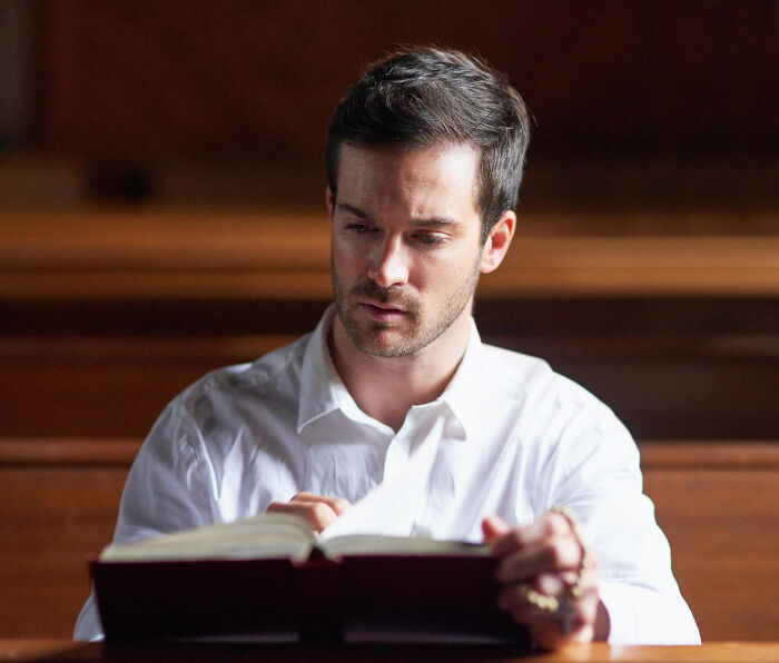 Man in white shirt reading a book, reflecting the experiences of people with disabilities facing rude and ableist behavior.