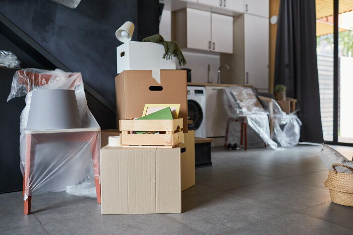 Stacked moving boxes with wrapped furniture in a modern home interior, illustrating tips for easier moving and packing.
