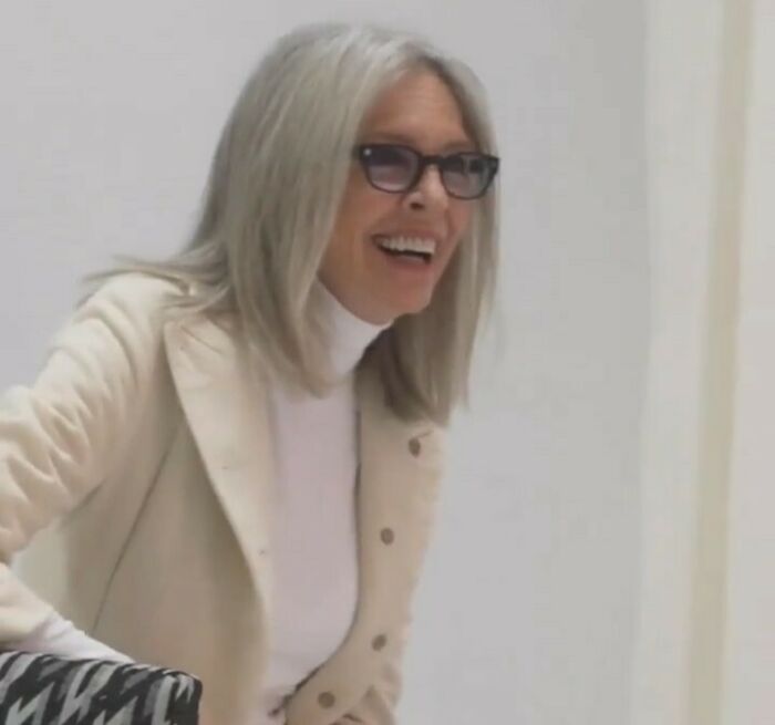 Diane Keaton smiling indoors wearing glasses and a cream jacket, related to Diane Keaton cause revealed after unexpected passing.