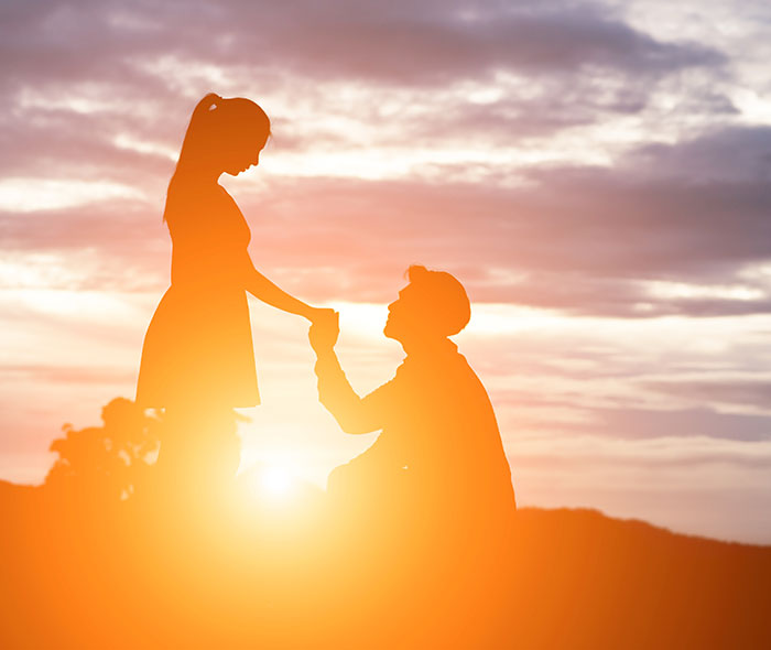 Silhouetted couple at sunset, man holding woman's hand in romantic pose, relating to cousin marriage benefits topic.