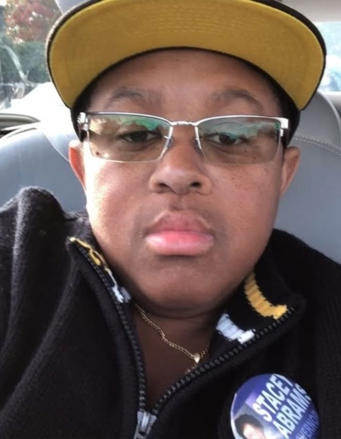 Close-up of a man wearing glasses and a yellow cap, illustrating famous men who are much shorter than fans imagined.