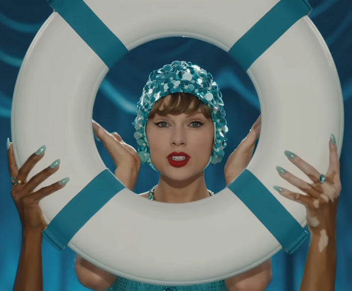 Taylor Swift in a shimmering swim cap holding a lifebuoy, hinting a secret jab at her ex in new music video.