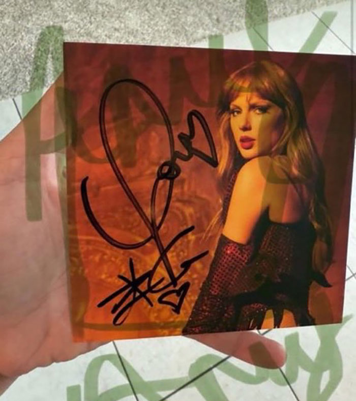 Hand holding a Taylor Swift album signed by Travis Kelce, sparking tradwife Taylor Swift fans' fury over autograph.