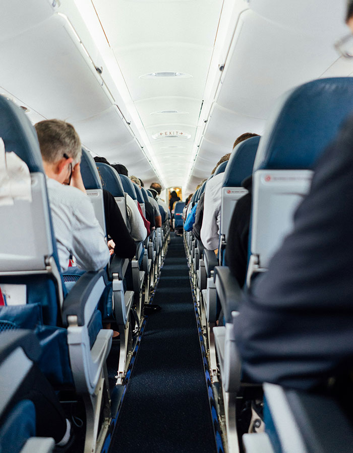 Airplane interior with passengers seated, illustrating a tense moment related to husband&rsquo;s infidelity mid-flight confrontation.
