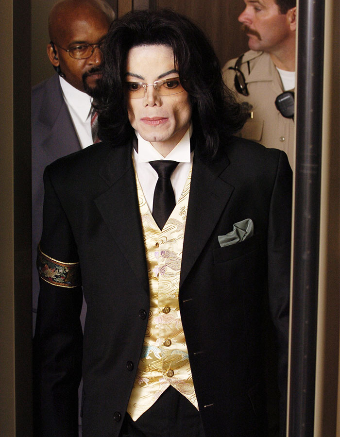 Michael Jackson wearing a suit and gold vest, escorted by security, linked to daughter Paris contacting father's alleged victims. Michael Jackson wearing a suit and gold vest, escorted by security, linked to daughter Paris contacting father's alleged victims.
