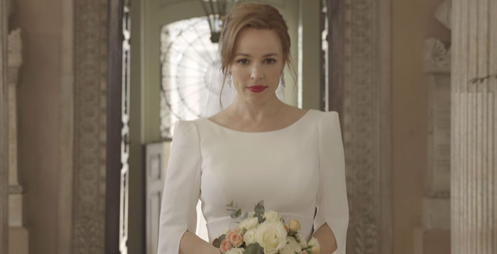 Rachel Mcadams in a natural look wearing a white dress, holding a bouquet, standing in an elegant architectural setting. Rachel Mcadams in a natural look wearing a white dress, holding a bouquet, standing in an elegant architectural setting.