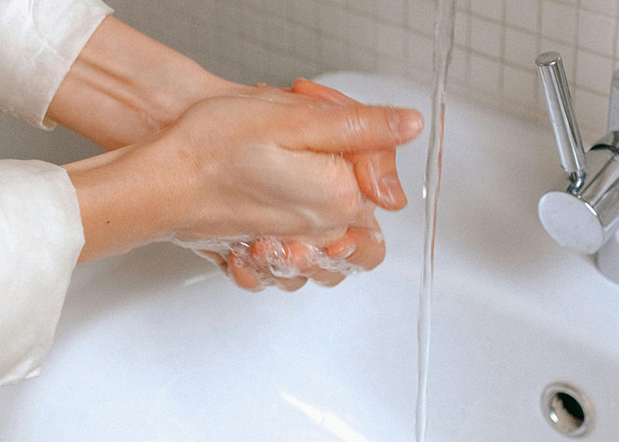 Person washing hands under running water in a white sink highlighting mental health myths awareness and hygiene importance.